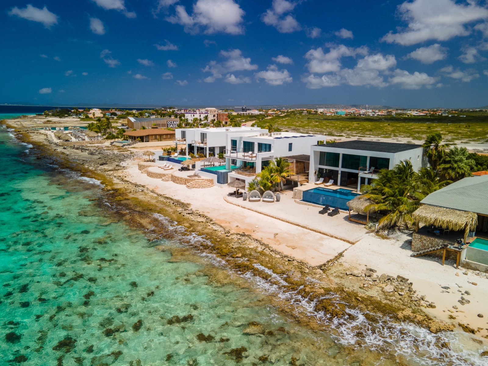 Aerial view of luxury Bonaire oceanfront villas with private infinity pools on the turquoise Caribbean coast.